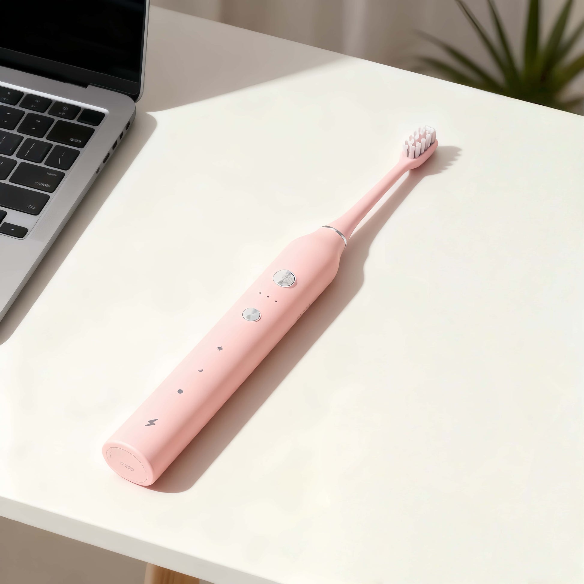 Orateeth pink toothbrush on desk with laptop